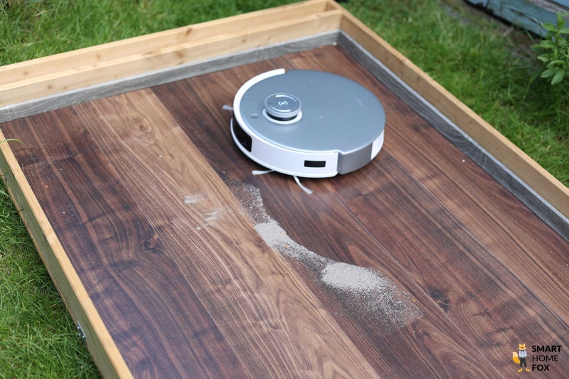 ECOVACS DEEBOT T20 OMNI reinigt im Saugtest Sand auf einem Hartboden.
